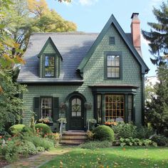 a green house with lots of windows and plants in front of the door is surrounded by greenery