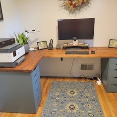 a desk with a computer on top of it in a room filled with wood floors