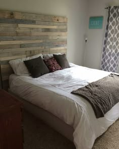 a bedroom with a bed made out of wooden planks and pillows on the headboard