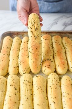 a person is holding a piece of bread in front of them on a baking sheet