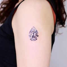 a woman with a tattoo on her arm has a diamond in the shape of a tear