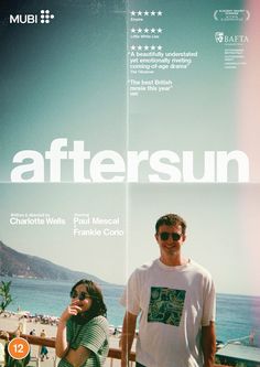 a man and woman standing next to each other in front of a poster for the film aftersun