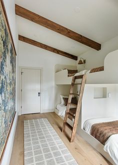 two bunk beds with ladders in a bedroom next to a rug on the floor