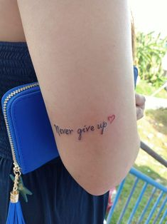 a woman's arm with the words never give up written in cursive writing