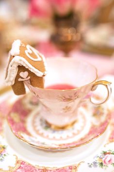 there is a small gingerbread house in the cup on top of a saucer