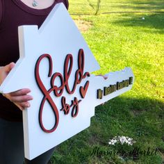 a woman holding up a sign that says sold