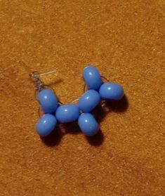 a pair of earrings with blue beads sitting on top of a brown table next to a cell phone