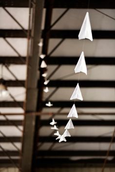 several white paper airplanes hanging from the ceiling