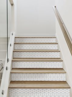 a set of stairs with wooden handrails and tiled flooring in a home