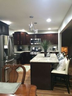 a kitchen with dark wood cabinets and stainless steel refrigerator freezer, stove top oven, microwave, dishwasher and dining room table