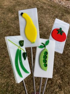 four pieces of glass with vegetables on them in the shape of fruit and veggies