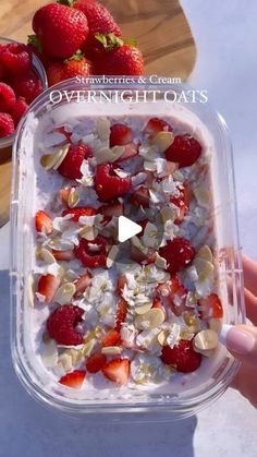 someone is holding up a plastic container filled with strawberries and almonds on top