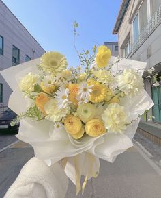 a bouquet of yellow and white flowers in front of a building