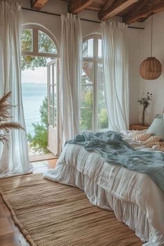 a large bed sitting in a bedroom next to an open window with white drapes