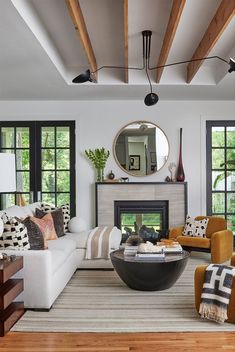 a living room filled with furniture and a fire place in front of a mirror on the wall