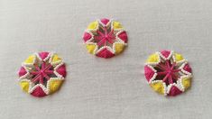 three pieces of crocheted fabric sitting on top of a white cloth covered table