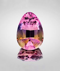 an oval shaped pink and purple diamond on a reflective surface with reflection in the middle