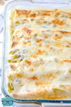 a casserole dish with cheese and vegetables in it sitting on a tablecloth