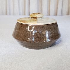 a brown and white bowl with a wooden spoon in it's top on a table