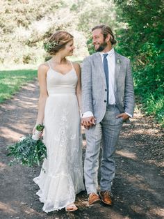 a bride and groom walking down a path holding hands