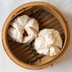 three dumplings in a bamboo basket on a white surface