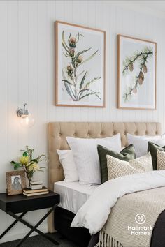 a bed with white linens and pillows in a bedroom next to two pictures on the wall