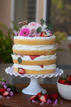 a cake with strawberries and flowers is on a table next to some other fruit