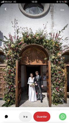 a man and woman standing in front of an open door with flowers on the wall