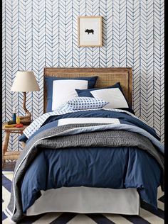 an image of a bedroom with blue and white decor on the walls, bedding and pillows