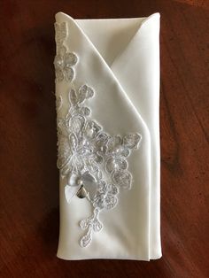 a white napkin with lace and buttons on it sitting on top of a wooden table