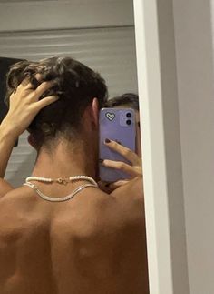 a man is taking a selfie in the mirror with his cell phone and wearing a pearl necklace