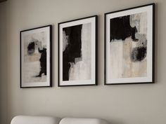 three black and white paintings hang on the wall next to a couch in a living room