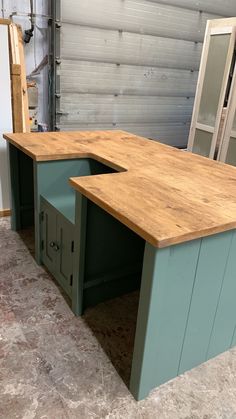 a large wooden desk sitting inside of a garage next to a door and window on the floor