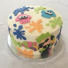 a decorated cake on a clear plate with white tablecloth and blue, green, yellow, orange and pink decorations