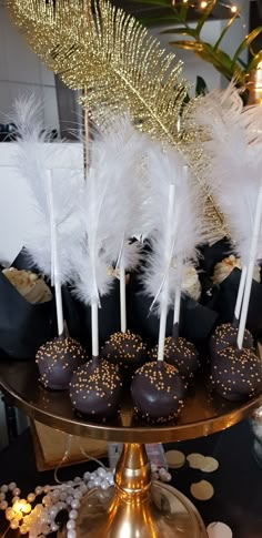 chocolate covered donuts on a gold platter with white feathers