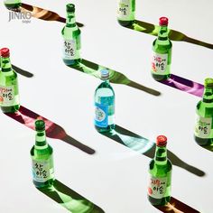 several bottles of water are lined up in the same direction on a white surface with long shadows