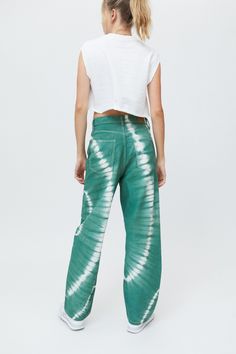 a woman standing in front of a white background wearing green tie dye pants