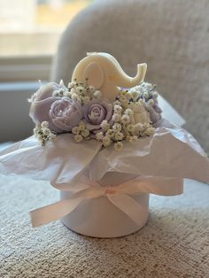 a bouquet of flowers in a white box on the floor next to a window sill