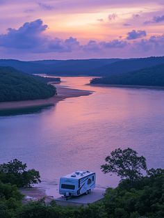 an rv is parked on the shore of a lake at sunset or dawn with clouds in the sky