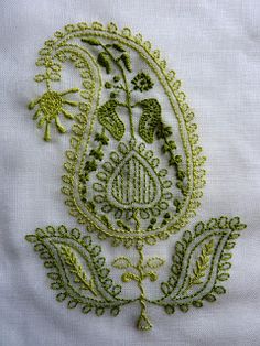 an embroidered piece of cloth with green flowers and leaves