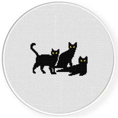 three black cats cross stitched together on a white circle with yellow eyes and tail