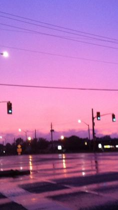 an intersection at dusk with traffic lights and street signs in the foreground, on a rainy day