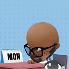 a man with glasses sitting at a desk in front of a sign that says mon