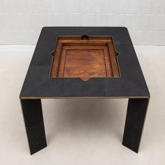 a black and gold coffee table with a square wooden tray on it's top