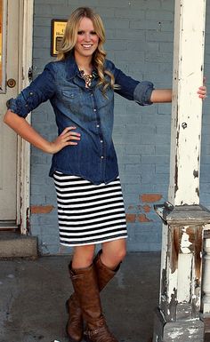 a woman standing in front of a door with her hands on her hips and wearing boots