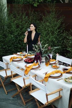 a woman standing in front of a long table with plates and glasses on top of it