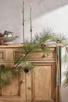 pine branches and candles are on top of an old dresser