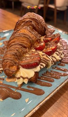 a sandwich with chocolate sauce, strawberries and ice cream on it sitting on a blue plate