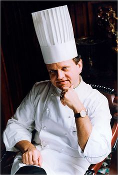 a man sitting in a chair wearing a chef's hat and looking at the camera