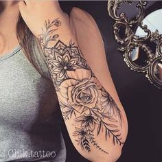 a woman's arm with flowers and leaves tattoo on her left arm, next to a mirror